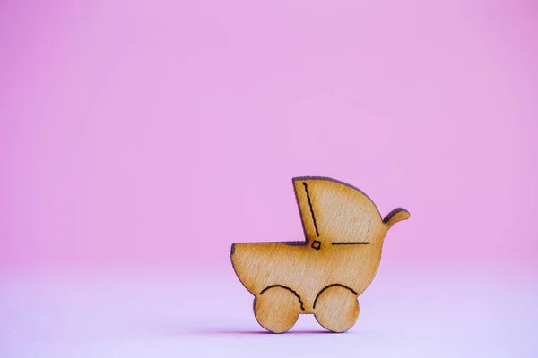 Деревянная икона детской коляски на розовом фоне — стоковое фото