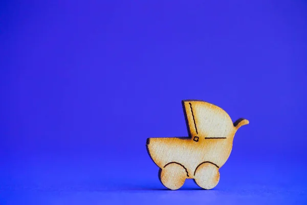 Деревянная икона детской коляски на синем фоне — стоковое фото
