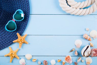 Şapka ve güneş gözlüğü kabukları, starfishes ve mavi ahşap üzerine ip ile
