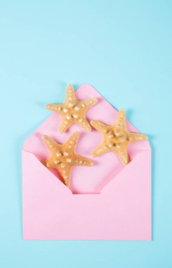 Pembe renkli nane mavi backgro üzerinde üç starfishes zarfla