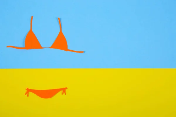 Orange paper bikini swimsuit on blue and yellow background. Mini — Stock Photo, Image
