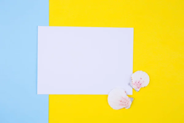 Arkuszu papieru puste z dwóch powłoki muszelki na kolorowe tło — Zdjęcie stockowe