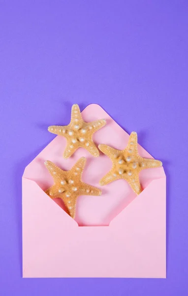 与彩色紫色背景上的三个海星粉色信封 — 图库照片