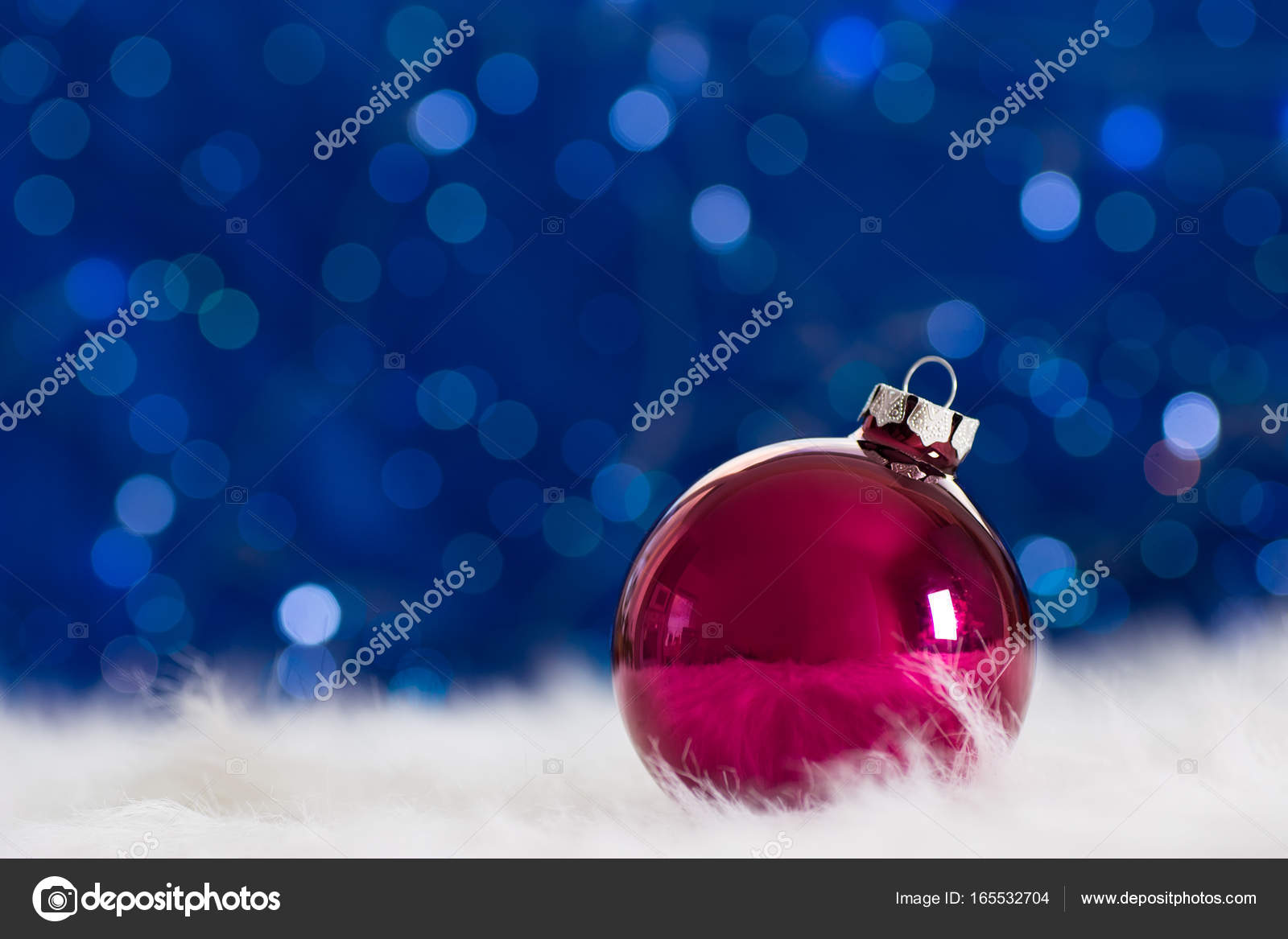 Burgundy Christmas Ball On White Fur With Garland Lights On Blue