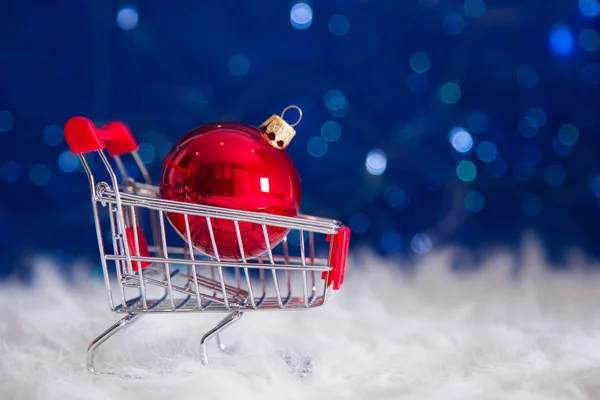 Boule de Noël rouge dans un petit chariot de supermarché sur bokeh ba bleu — Photo