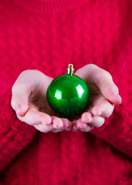 Όμορφη Χριστουγεννιάτικη μπάλα στα γυναικεία χέρια σε φόντο κόκκινο kn — Φωτογραφία Αρχείου