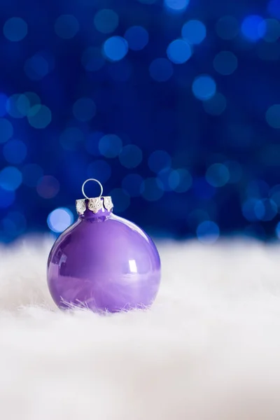 Liliowy Boże Narodzenie ball na białe futro z świateł girlanda na niebieski bo — Zdjęcie stockowe