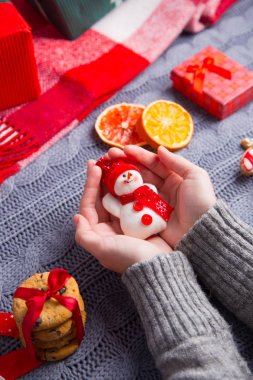 Kadın elinde oyuncak kardan adam bedeni üzerinde tutarak gri örgü kazak