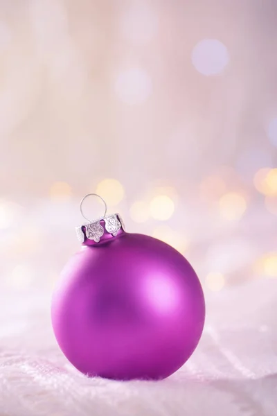 Boule de Noël violette sur dentelle blanche sur bokeh arrière léger et chaud — Photo