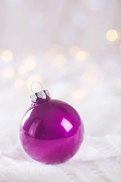 Boule de Noël violette sur dentelle blanche sur bokeh arrière léger et chaud — Photo