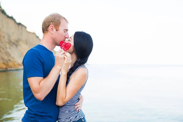 Romántico joven caucásico pareja besándose en la playa ocultándose ser — Foto de Stock