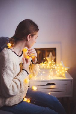 Parlayan garland kapalı tutarak kazaklı genç ve güzel kadın