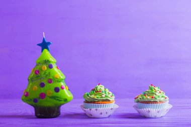 Kremsi yeşil top ve Christm şeklinde mum ile iki cupcakes