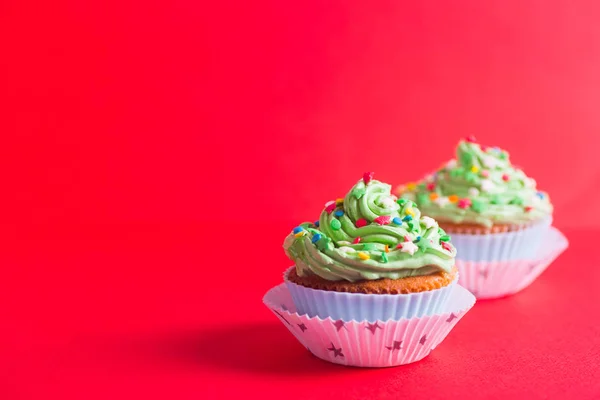Dos cupcakes con tapa verde cremoso con estrellas de colores y sprin — Foto de Stock