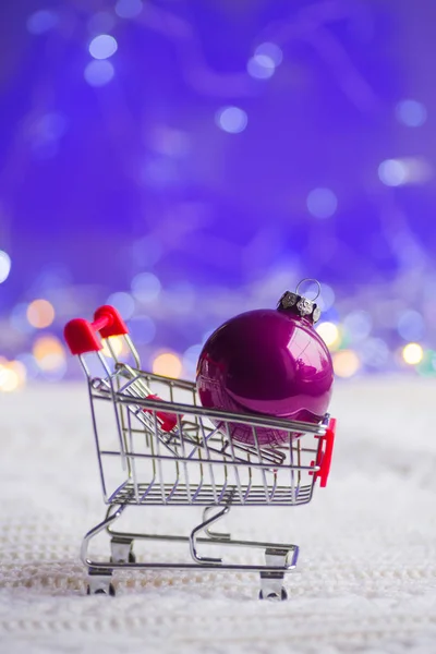 Boule de Noël violette dans un petit chariot de supermarché avec guirlande — Photo