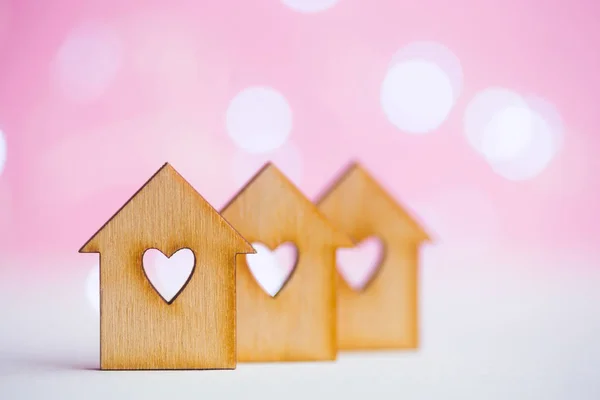Tre trä hus med hål i form av hjärta på rosa bokeh bac — Stockfoto