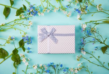 Mavi ve beyaz küçük çiçeklerle çevrili beyaz hediye kutusu 