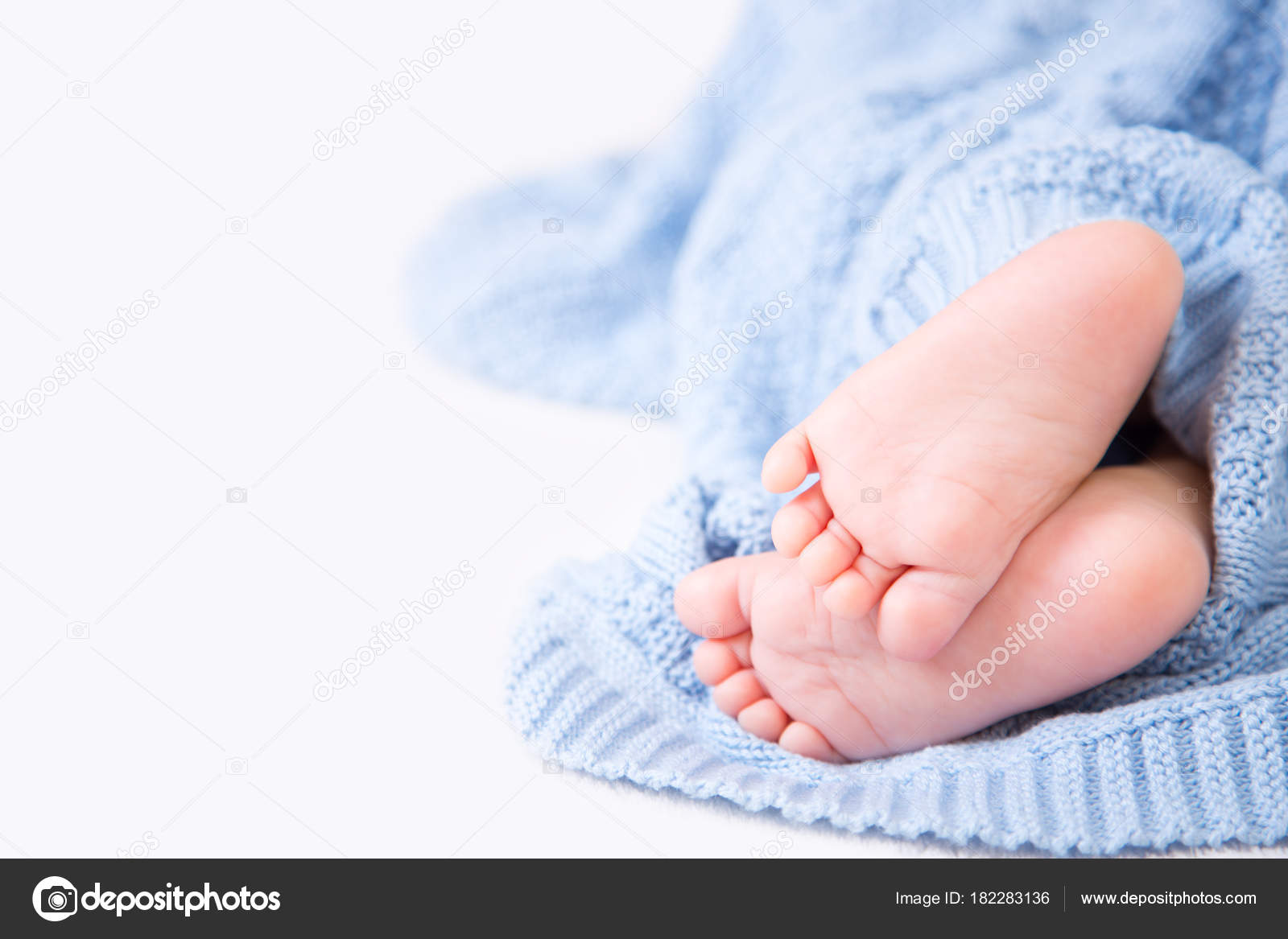 Barfuß zarte Babyfüße in blauem Strickkariert auf weißem Hintergrund