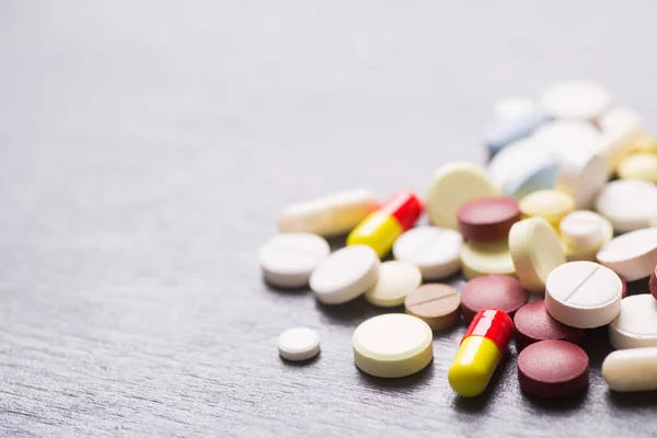 Kolorowe różne kapsułki i tabletki na szarym tle — Zdjęcie stockowe