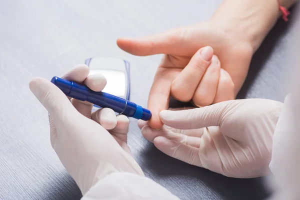 Doctor's hand in medical latex glove checking patient's blood glucose level using syringe pen — Stock Photo, Image