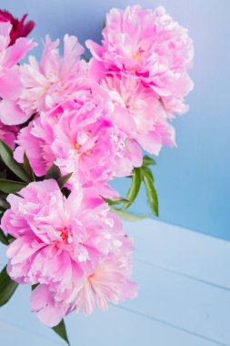 Mavi ahşap zemin üzerine cam vazoda güzel pembe peonies yemyeşil buket