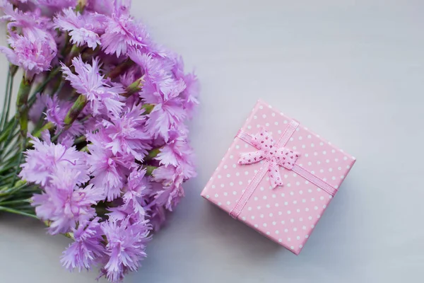Buquê de flores de cravo rosa concurso com caixa de presente em fundo claro à luz do dia — Fotografia de Stock