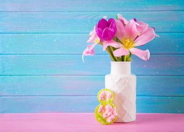 Figure décorative huit et bouquet tendre de belles tulipes dans un vase sur fond de bois bleu — Photo