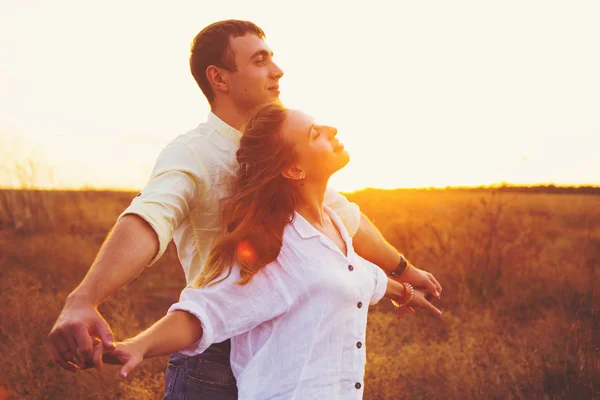 Joven pareja romántica cogida de la mano disfrutar de rayos de sol al aire libre en el campo — Foto de Stock