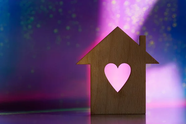 木制图标的房子与孔的心脏形式的粉红色和紫色黑暗的银河背景与光Bokeh 有复制空间的浪漫卡片 甜蜜家庭的概念 图库图片