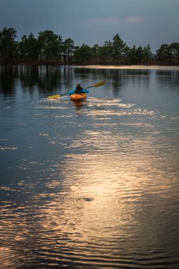 Çocuk akşamları nehirde kanoda yüzüyor.