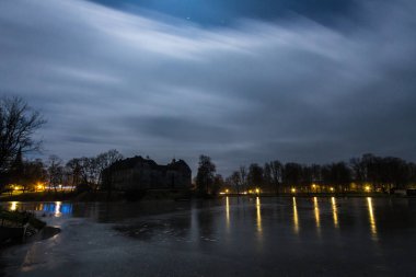 Akşam vakti nehir kıyısında eski bir bina. 