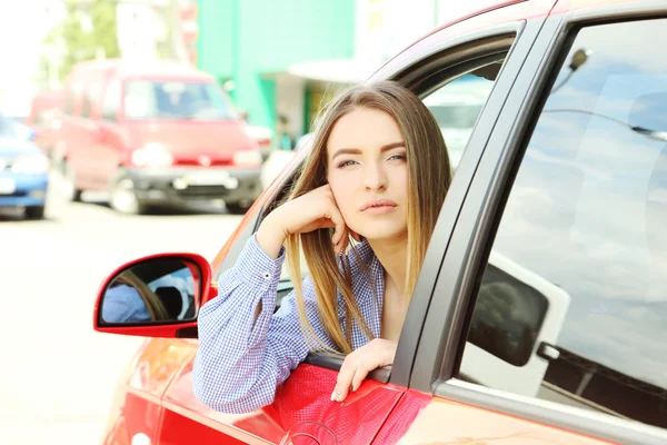 Młoda dziewczyna siedzi w samochodzie czerwony — Zdjęcie stockowe