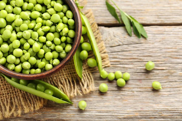 Guisantes verdes en mesa de madera — Foto de Stock