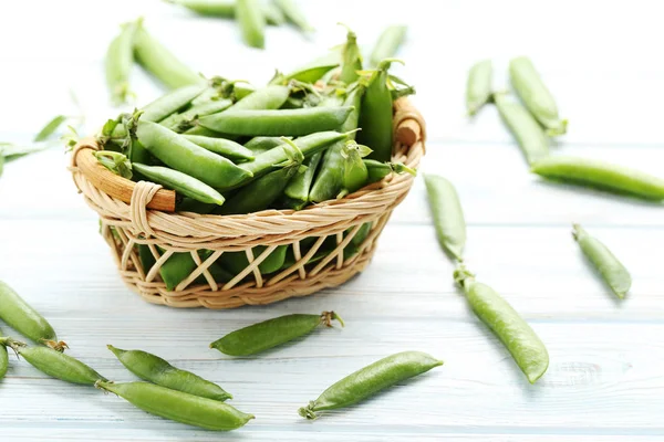 Ervilhas verdes em uma mesa azul — Fotografia de Stock