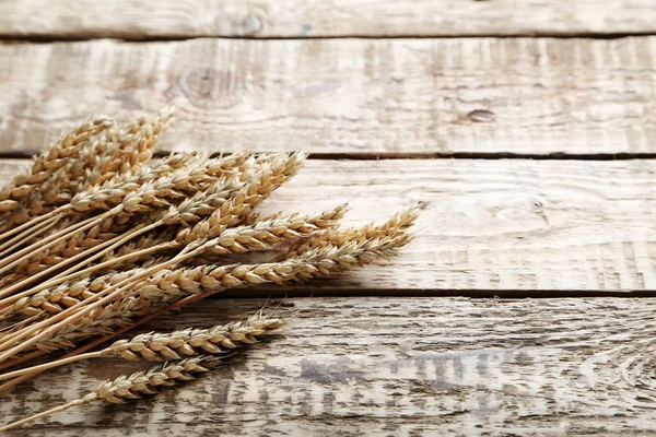 Ears of wheat on wooden table — Stock Photo, Image