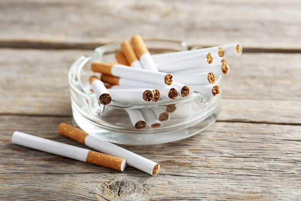 Tabaco cigarrillos en cenicero de vidrio —  Fotos de Stock