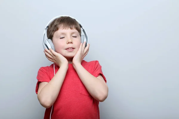 Retrato de niño con auriculares sobre fondo gris — Foto de Stock