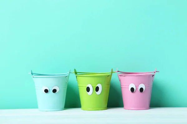 Colorful buckets with googly eyes — Stock Photo, Image