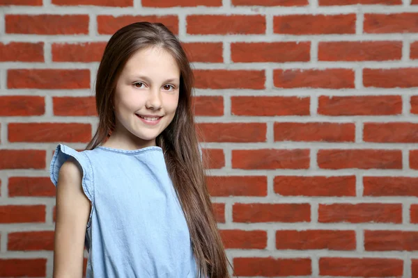 Porträtt av ung flicka på tegel vägg bakgrund — Stockfoto