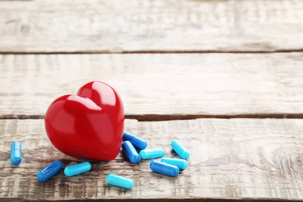 Pastile albastre capsule cu inimă roșie — Fotografie, imagine de stoc