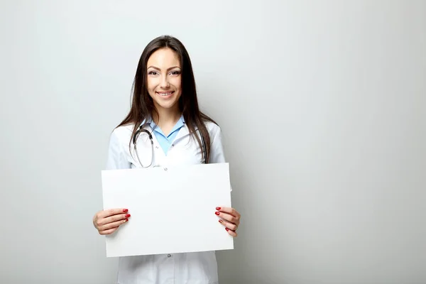 Porträt eines jungen Arztes mit Blatt auf leerem Papier auf einem — Stockfoto
