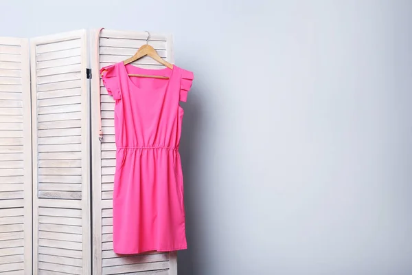 Vestido rosa pendurado na tela dobrável — Fotografia de Stock