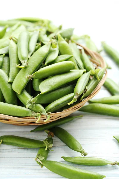 Green peas in wicker bowl — Stock Photo, Image