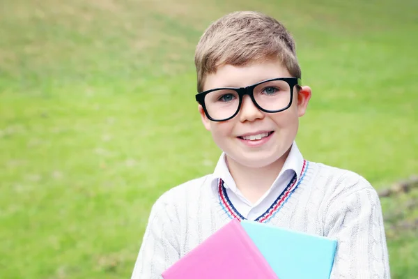 Portret van de jonge jongen met bril en boeken in het park — Stockfoto