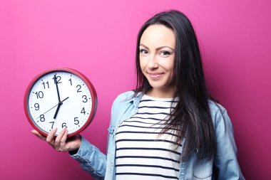 Genç bir kadın saati tutuyor.