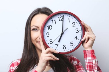 Genç bir kadın saati tutuyor.