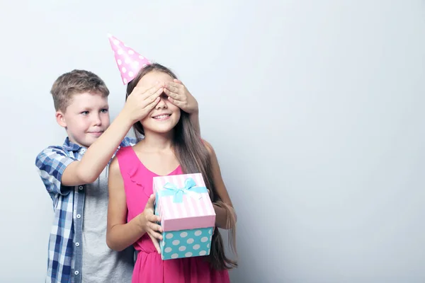 Junge bedeckt Augen von Mädchen, hält Geschenkbox — Stockfoto