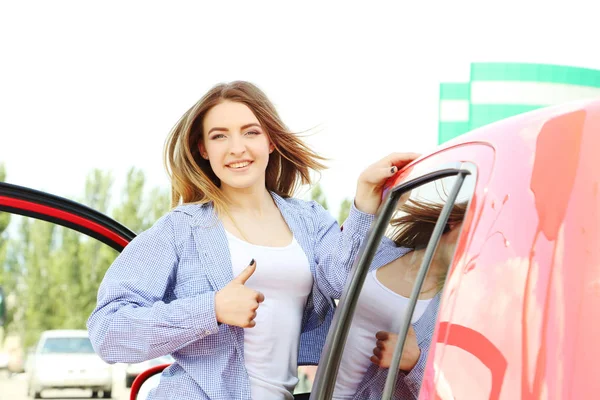 Vacker ung flicka stående nära ny röd bil — Stockfoto