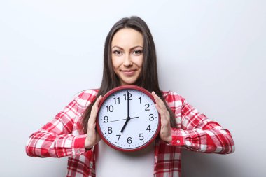 Genç bir kadın saati tutuyor. 