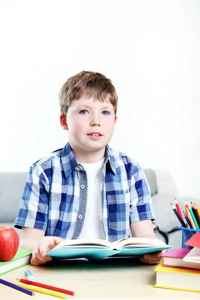 Ung pojke sitter vid skrivbordet och läsa bok — Stockfoto